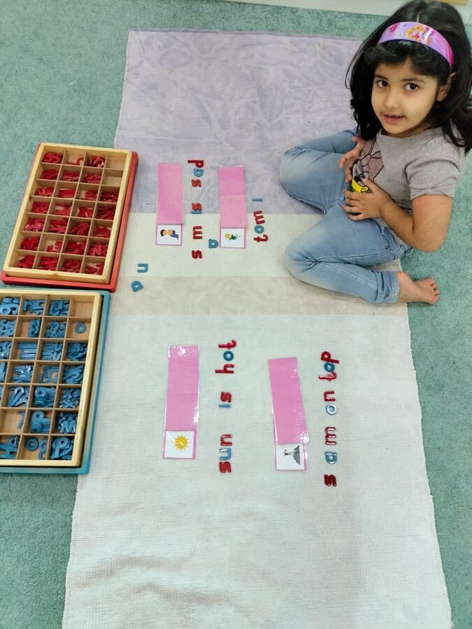 Child building sentences with the Montessori word-building strips